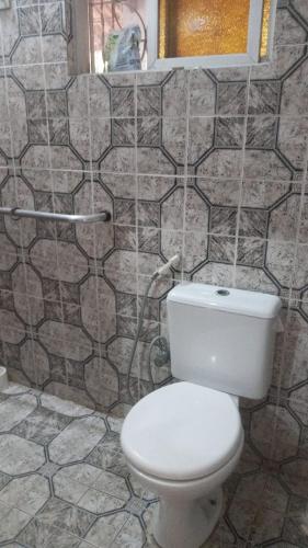 uma casa de banho com um WC e uma parede em azulejo em Casa grande mobiliada pra são joao em Campina Grande