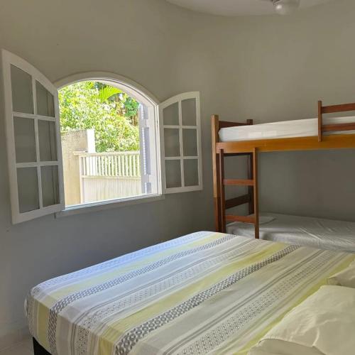 a bedroom with two bunk beds and a window at Tenório Beach Hostel 400 MTS da praia do Tenório in Ubatuba
