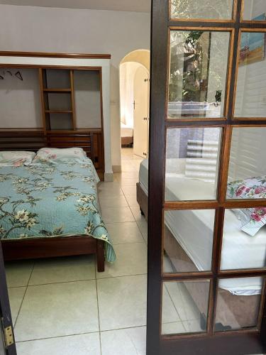 a bedroom with a bed next to a glass door at Tenório Beach Hostel 400 MTS da praia do Tenório in Ubatuba