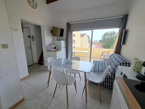 une cuisine avec une table et des chaises dans une pièce dans l'établissement Appartement lumineux avec terrasse, proche plage et commodités, Marseillan-Plage - FR-1-326-821, à Marseillan