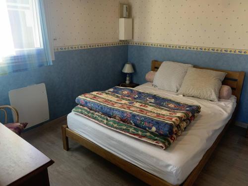 un lit avec une couette dessus dans une chambre dans l'établissement Duplex cosy 4 personnes avec parking, proche plage - Merville Franceville - FR-1-465-112, à Merville-Franceville-Plage