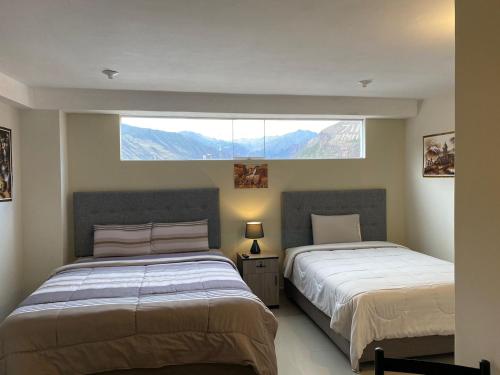 2 Betten in einem Schlafzimmer mit einem großen Fenster in der Unterkunft Plaza del Inka in Urubamba