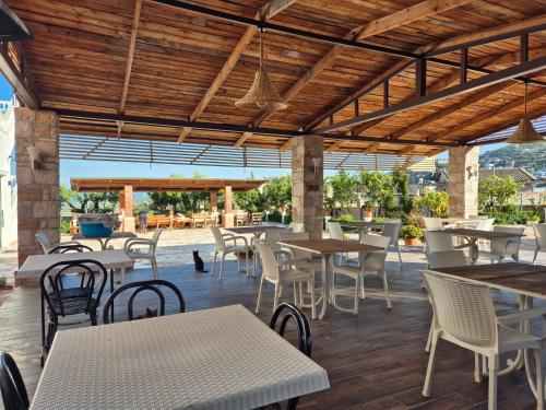 een openluchtrestaurant met tafels en stoelen en een houten plafond bij Villa JOSANA in Sarandë