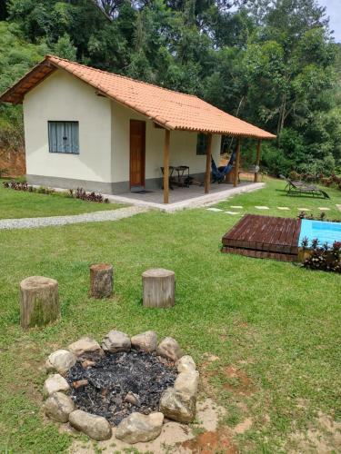 a house with a fire pit in the yard at Chalé encontro dos rios in Nova Friburgo