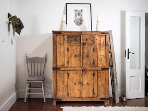 an old wooden cabinet in a room with a chair at Country Oasis With River Views in Cygnet
