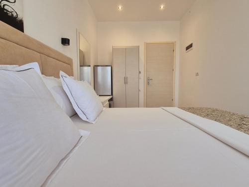 una camera da letto con un grande letto bianco con cuscini bianchi di Villa JOSANA a Sarandë