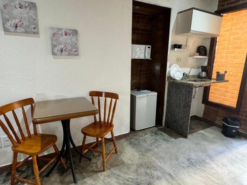 uma pequena cozinha com uma mesa e duas cadeiras em Chalé 09 com cozinha no coração de penedo em Itatiaia
