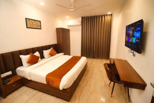 Habitación de hotel con cama y TV en Sandhu Lodge en Jamnagar