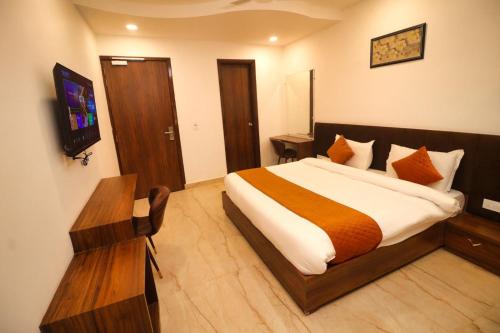 a bedroom with a bed and a television in it at Sandhu Lodge in Jamnagar