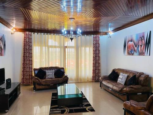 a living room with leather furniture and a chandelier at Quiet and Spacious Hidden Gem in Kigali with Breathtaking Views right by the Airport in Kigali
