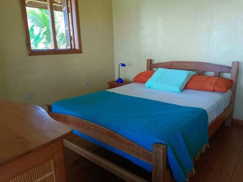 1 dormitorio con 1 cama con almohadas azules y naranjas en Casa Ylang, en Bastimentos