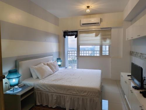 a bedroom with a bed and a window and a television at 2 Bedroom Condo SMDC Breeze Residences in Manila