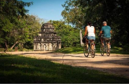 un hombre y una mujer montando bicicletas por un camino de tierra en ARANI HOMESTAY, en Polonnaruwa