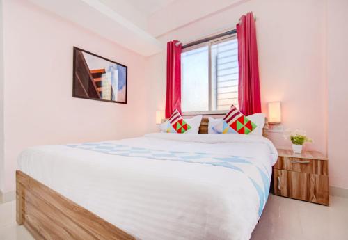 1 dormitorio con 1 cama grande y cortinas rojas en OYO Dhage's Homestay en Pune