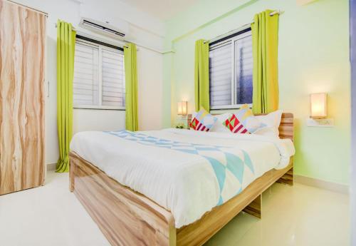 1 dormitorio con 1 cama grande y cortinas verdes en OYO Dhage's Homestay, en Pune