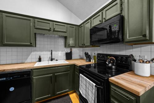 a kitchen with green cabinets and a black stove top oven at Escape to Sugar Chalet: The Rustic Modern Retreat in Gatlinburg
