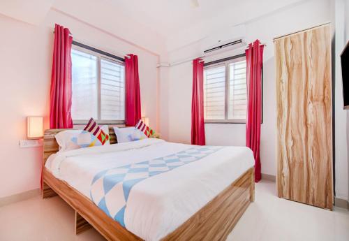 una camera da letto con un grande letto con tende rosse di OYO Dhage's Homestay a Pune