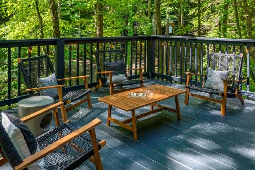 a wooden deck with chairs and a wooden table at Escape to Sugar Chalet: The Rustic Modern Retreat in Gatlinburg