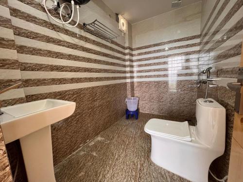La salle de bains est pourvue de toilettes blanches et d'un lavabo. dans l'établissement Sharma Farms, à Jamnagar