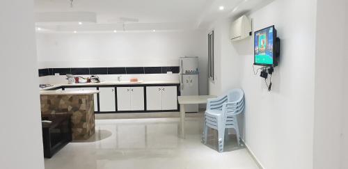 a white kitchen with a table and two chairs at Résidence Wissem in Ḩammām al Ghazzāz