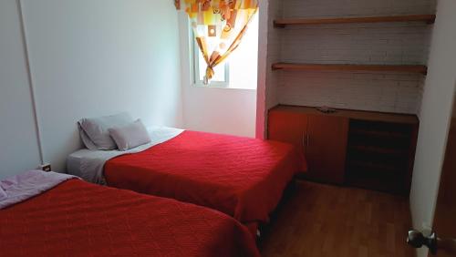 um quarto com duas camas com lençóis vermelhos e uma janela em Las flores Boulevard em Cidade do México