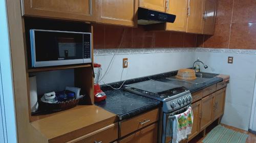 eine kleine Küche mit einem Herd und einer Mikrowelle in der Unterkunft Las flores Boulevard in Mexiko-Stadt