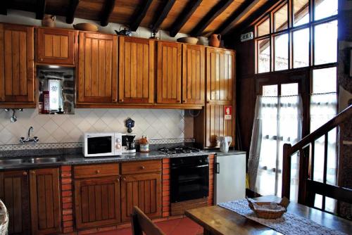 a kitchen with wooden cabinets and a white microwave at Casa do Forno in Valezim