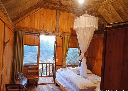 een slaapkamer met een bed en een groot raam bij Hill home Hoang Su Phi in Nam Pi