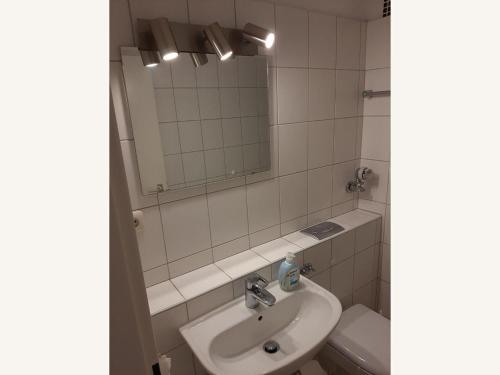 uma casa de banho com um lavatório, um espelho e um WC. em Fritz-Wischer-Strasse-Whg-01 em Sankt Peter-Ording