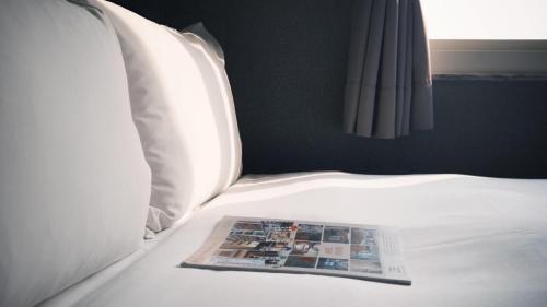 a magazine sitting on top of a bed at Hotel Leisure 台中輕行旅 in Taichung