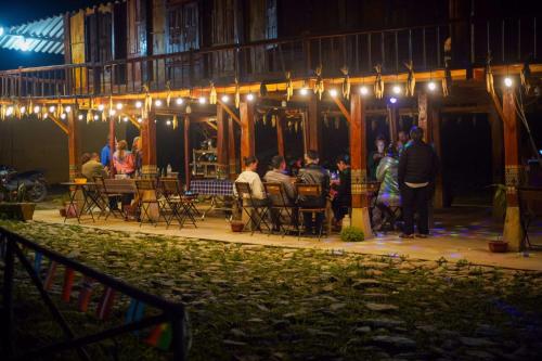 a group of people sitting at tables under lights at Du Già Coffee View Homestay in Làng Cac