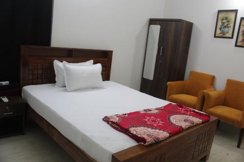 a bedroom with a bed and two orange chairs at Friendlystay Prime in Chennai