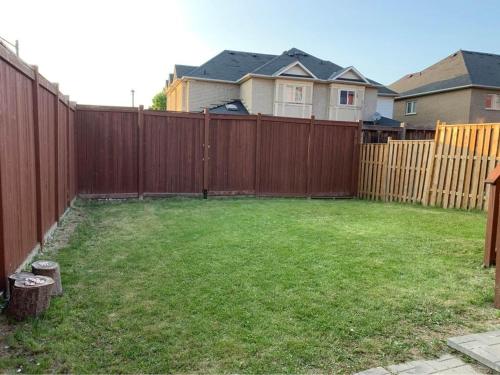 een achtertuin met een houten hek en een groene tuin bij Jazzy Apartment in Mississauga