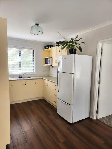 a white refrigerator in a kitchen with wooden floors at Karapiro Apartment in Cambridge