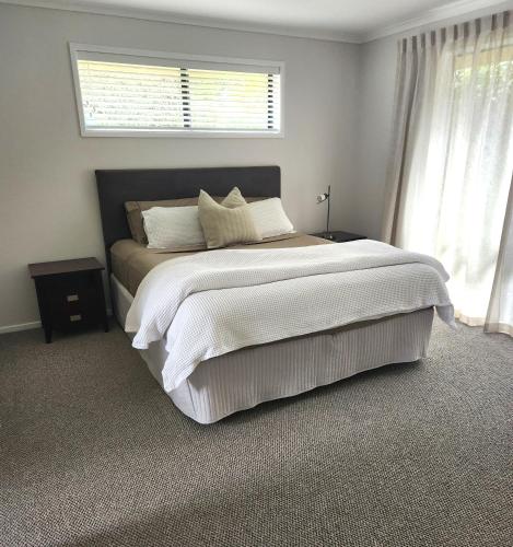 a bedroom with a large white bed with a window at Karapiro Apartment in Cambridge