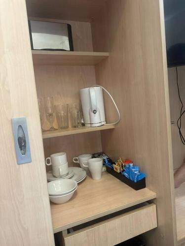 un pequeño armario con tazas y cuencos en un estante en Famous hotel Melbourne CBD, en Melbourne
