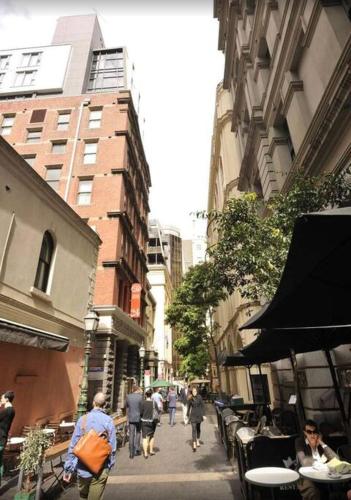 un grupo de personas caminando por una calle de la ciudad en Famous hotel Melbourne CBD, en Melbourne