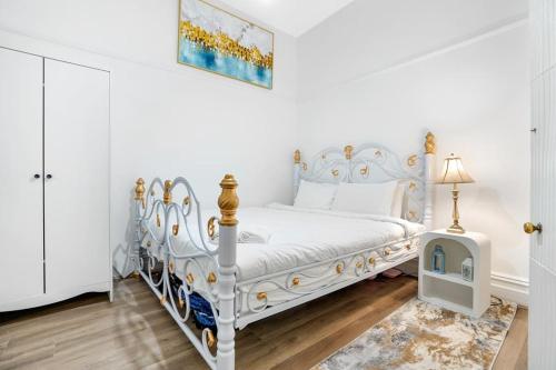 a white bedroom with a white bed with gold accents at Prime Modern Brilliance with Prahran Convenience in Melbourne