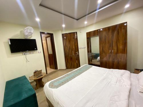 a bedroom with a white bed and a flat screen tv at MS RESORT in Dalhousie