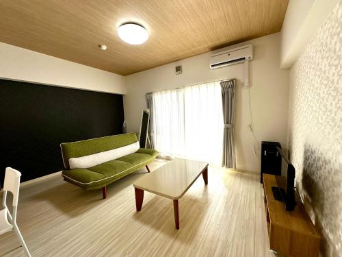 a living room with a green couch and a table at 札幌駅北口から徒歩圏内で好立地最大4名滞在可能な広い室内空間 in Kita-rokujō