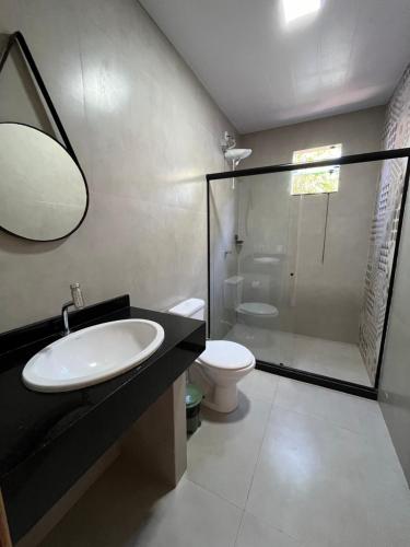uma casa de banho com um lavatório, um chuveiro e um WC. em Pousada Beluga em Búzios