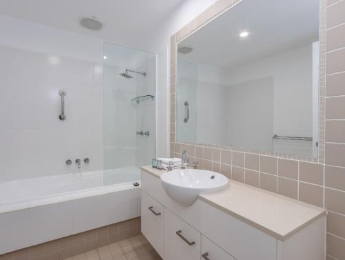 un bagno bianco con lavandino, vasca e doccia di Stunning She Oak Lane - 2 Bedroom Apartment! a Casuarina