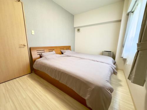 una camera da letto con un letto con lenzuola bianche e una finestra di 札幌駅北口から徒歩圏内で好立地最大4名滞在可能な広い室内空間 a Kita-rokujō