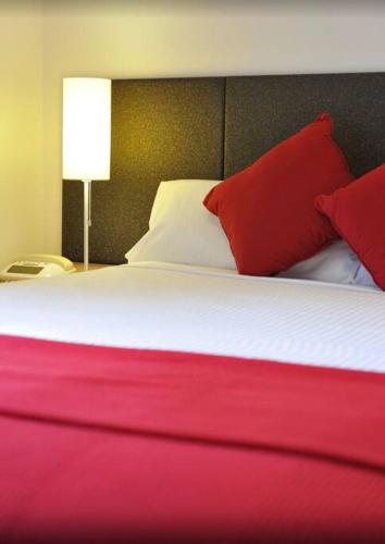 Cama grande con sábanas y almohadas rojas y blancas en Melbourne boutique hotel en Melbourne