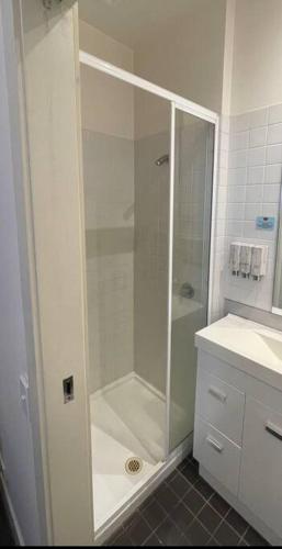 baño blanco con ducha y lavamanos en Melbourne boutique hotel en Melbourne