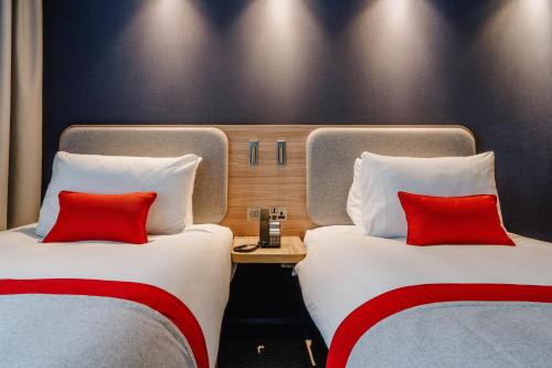 two beds with red pillows in a hotel room at Holiday Inn Express Liverpool - Central by IHG in Liverpool
