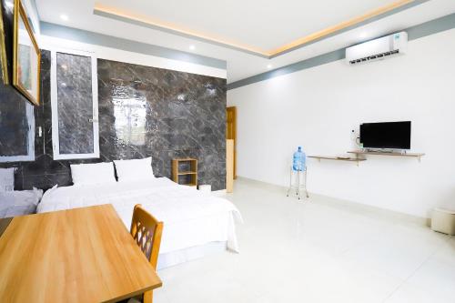 1 dormitorio con 2 camas, mesa y TV en Hotel Trâm Anh en Nhơn Trạch