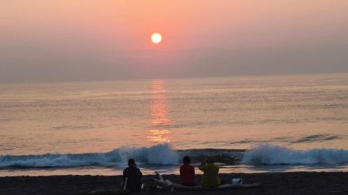 a group of people sitting on the beach watching the sunset at 一個人背包客棧 in Wujie