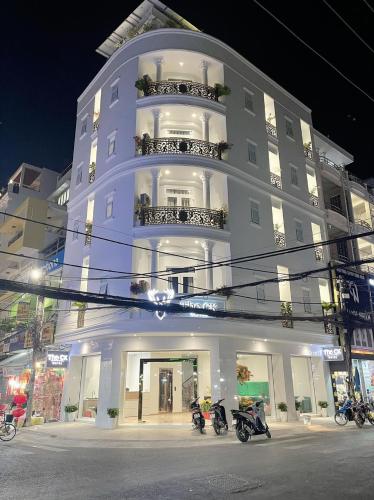 朱笃The CK Hotel的一座白色的建筑,前面停有摩托车