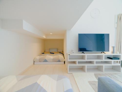 a white living room with a tv and a bed at YOUR ROOM Kumamoto Sta little 103 Vacation STAY 75704 in Kumamoto
